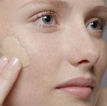 close up of part of young woman's face, applying concealer