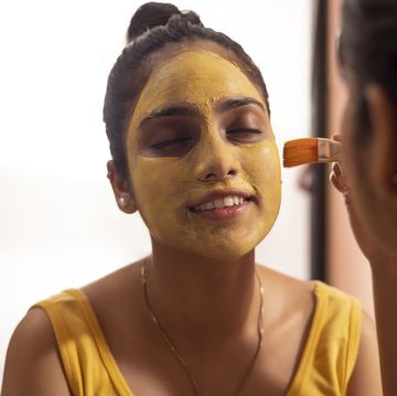woman applying turmeric face pack on her friend's face
